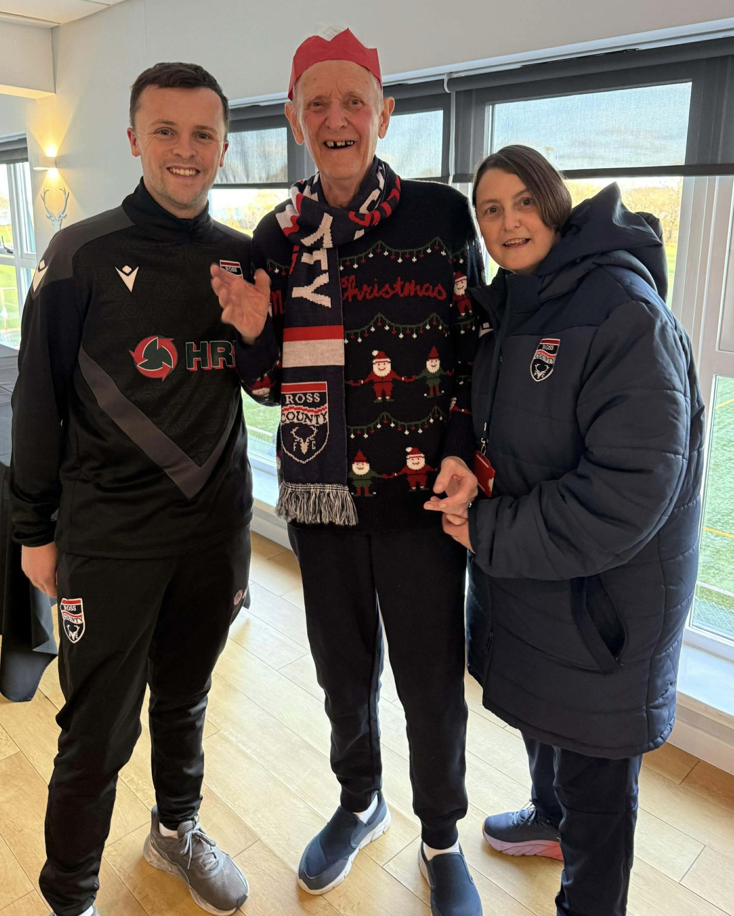 A resident in a Ross County scarf with two people from the club