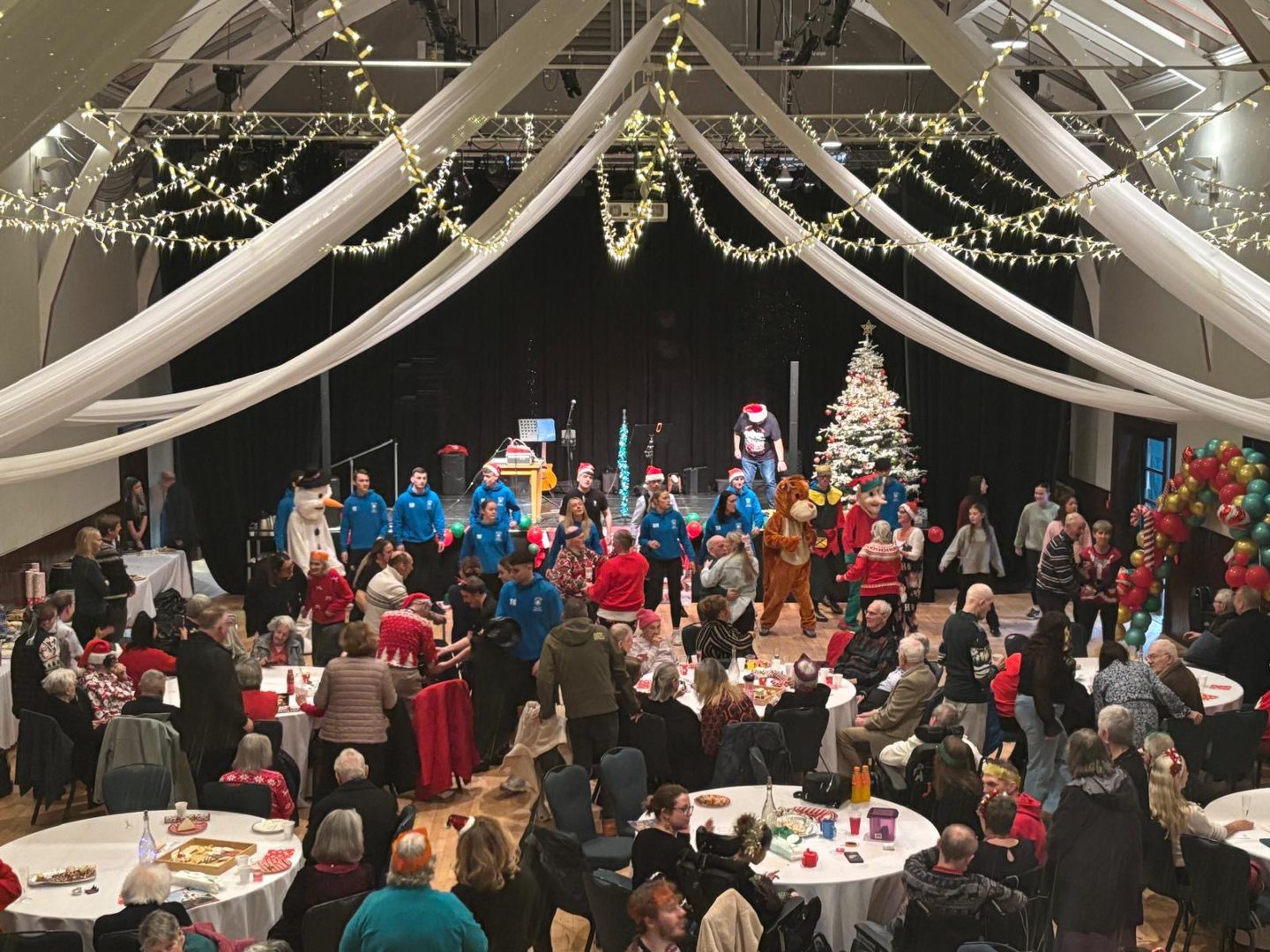 The Christmas party, with residents at tables and a stage beyond